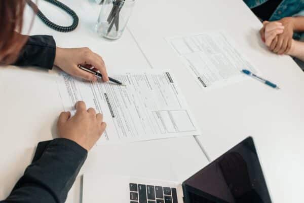 a-professional-meeting-with-document-signing-at-an-office-desk-focusing-on-teamwork - Adam C. Gynac & Associates LLC Prenuptial Attorney Services | Granholm Gynac Joliet IL Page 4