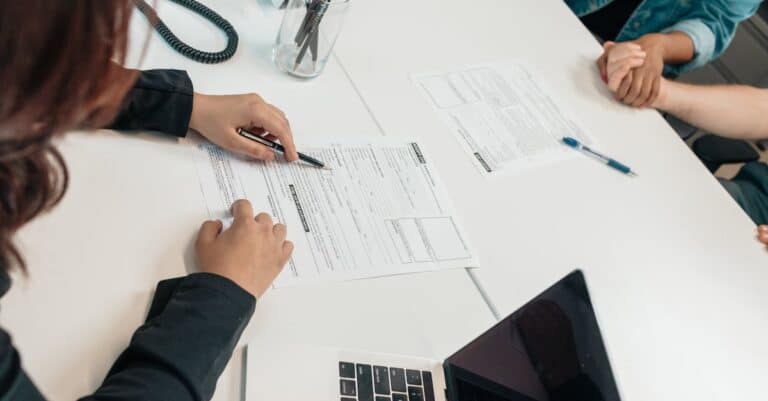 a-professional-meeting-with-document-signing-at-an-office-desk-focusing-on-teamwork - Adam C. Gynac & Associates LLC Prenuptial Attorney Services | Granholm Gynac Joliet IL