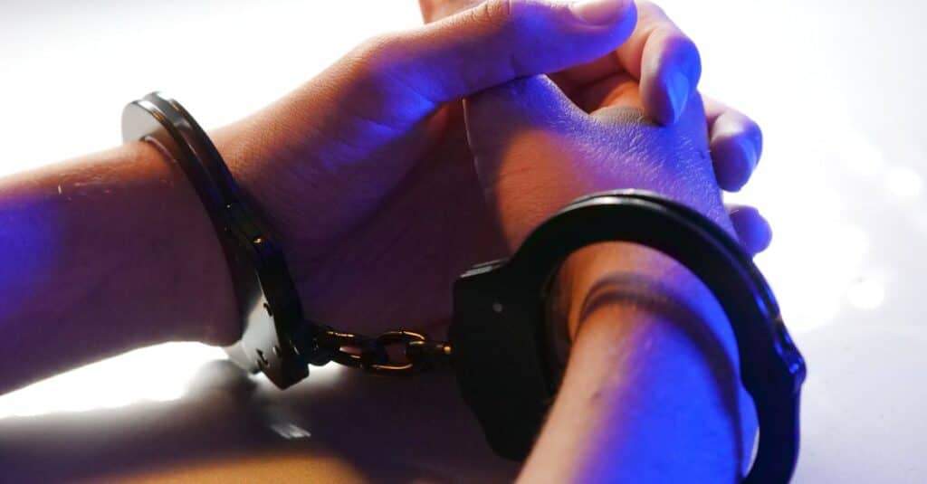 close-up-of-handcuffed-hands-under-blue-police-light-signifying-arrest-or-detention