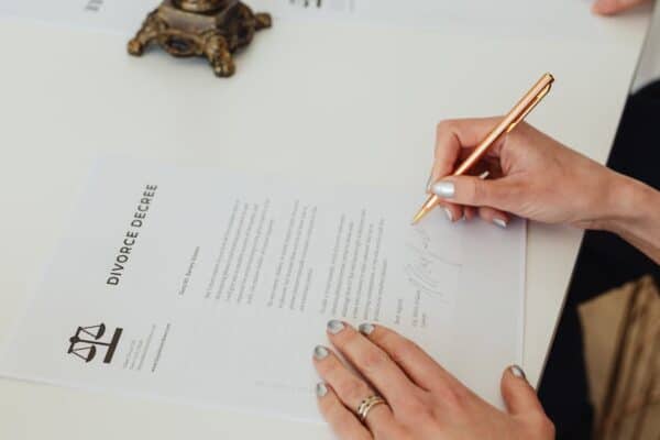 close-up-of-hands-signing-a-divorce-decree-document-on-a-desk-showcasing-legal-process - Adam C. Gynac & Associates LLC Divorce Parentage Decree Modifications | Adam C Gynac Associates LLC Page 3