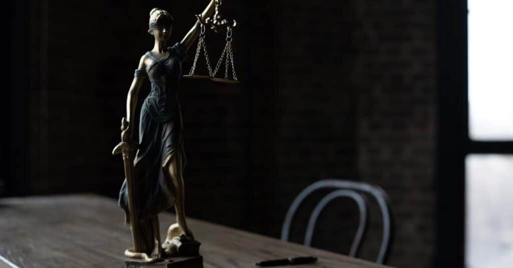 lady-justice-figurine-on-wooden-table-in-dimly-lit-room-symbolizes-law-and-fairness
