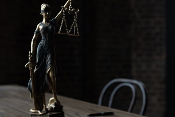 lady-justice-figurine-on-wooden-table-in-dimly-lit-room-symbolizes-law-and-fairness - Adam C. Gynac & Associates LLC Trust Attorneys | Estate Planning | Granholm Gynac Joliet IL Page 5